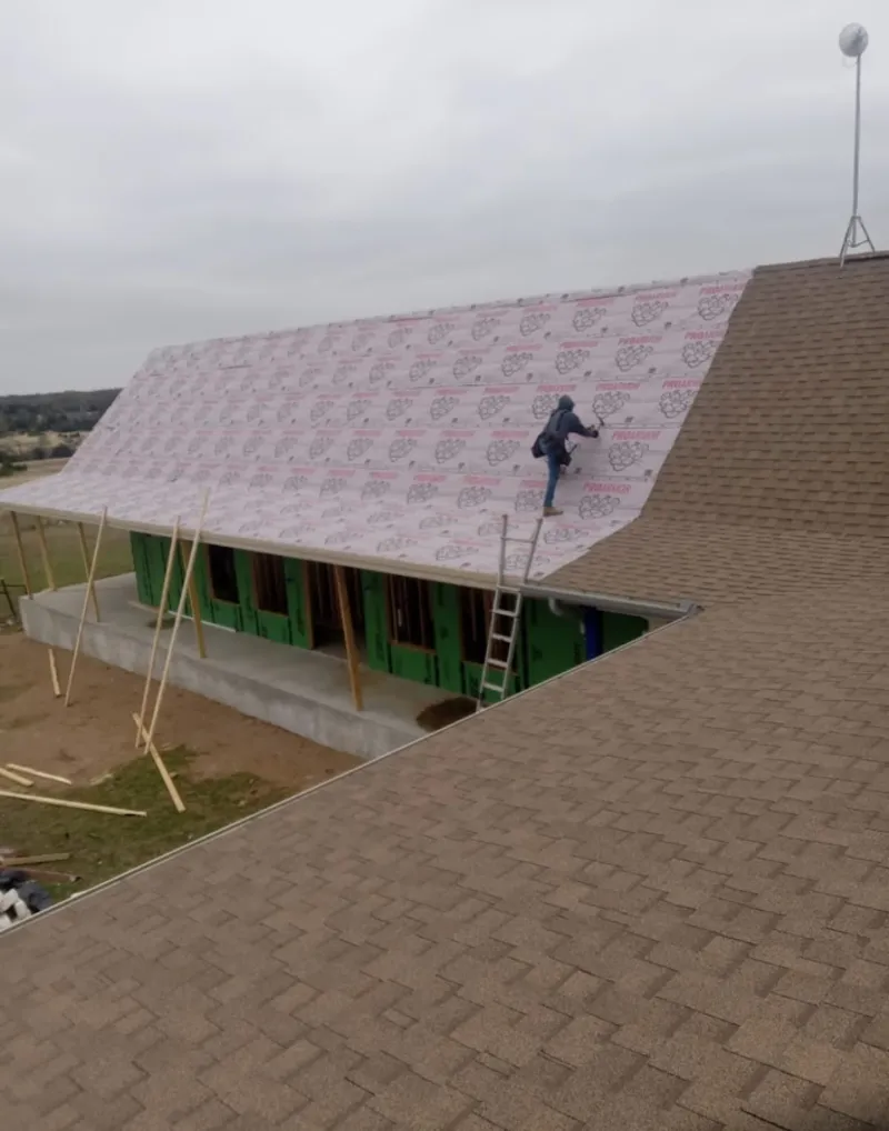 Worker preparing underlayment for a metal roof installation in Sanford